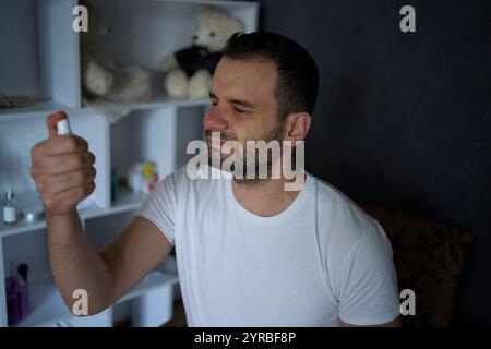 Der 30-jährige Mann trägt Spraytonic auf seine Haut auf Stockfoto