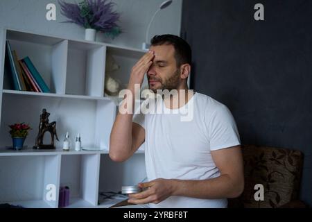 Der 30-jährige Mann trägt Feuchtigkeitscreme auf sein Gesicht auf Stockfoto