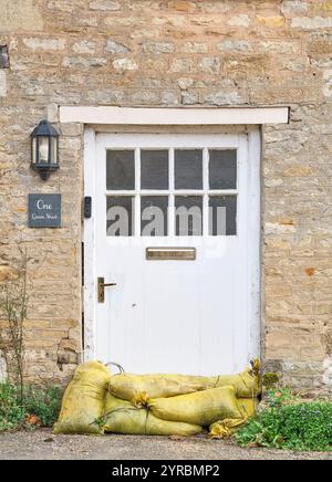 Sandsäcke am unteren Rand der Eingangstür an der One Queen Street im Dorf Geddington, England, zum Schutz vor Hochwasser durch starken Regen Stockfoto