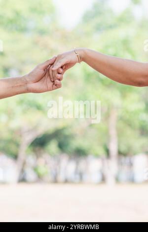 Ein junger Mann hält die Hand einer jungen Frau, die sein Geliebter ist, um seine Liebe zum Ausdruck zu bringen und zu versprechen, sich für immer zu lieben und für sich zu sorgen. Das Konzept Stockfoto