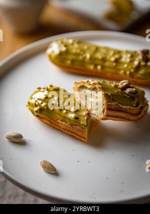 Pistazien-Eclairs mit hellgrüner Glasur auf weißer Platte Stockfoto