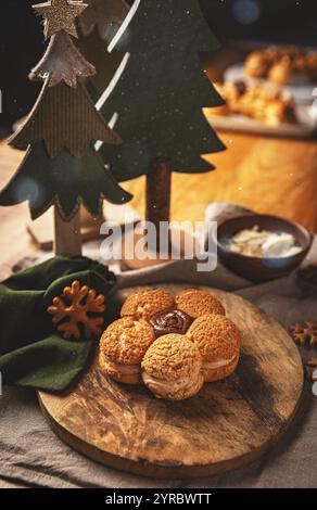 Cremefarbene Puffs in Blütenform auf Holzbrett, die süße und optisch ansprechende Leckereien bieten Stockfoto