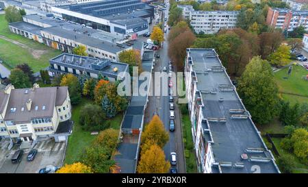 Aus der Vogelperspektive auf ein Wohngebiet mit Apartmentgebäuden, geparkten Autos und Bäumen in Herbstfarben. Stockfoto