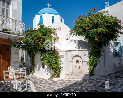 Eine klassische Szene auf den griechischen Inseln, weiße Häuser mit blauen Dächern, die mit Bougainvillea bedeckt sind Stockfoto