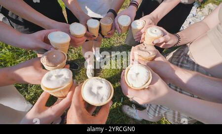 Eine Gruppe von nicht erkennbaren Menschen, die an einem sonnigen Sommertag Eiskegel in Waffelbechern halten. Stockfoto