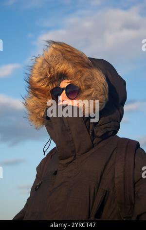 Porträt einer Frau, die draußen einen mit Pelz gefütterten Wintermantel trägt Stockfoto