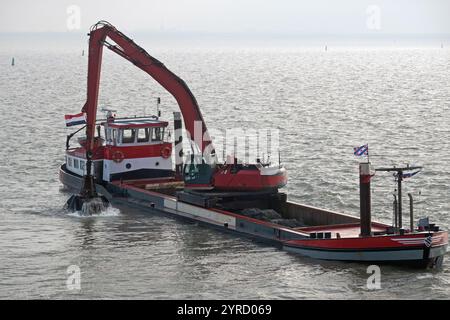 Red Baggerarbeiten Schiff arbeiten am Meer, Entfernen von Ablagerungen in einer Wasserstraße Stockfoto