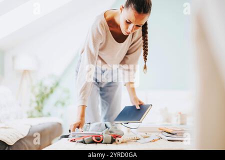 Junge Studentin organisiert Studienmaterialien zu Hause Stockfoto