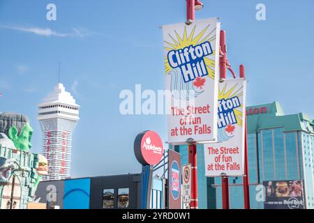 Helle Banner, die Clifton Hill, „The Street of Fun at the Falls“, mit Skylon Tower und Attraktionen im Hintergrund, werben. Stockfoto