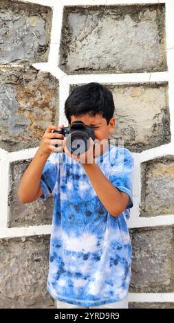 Der 10-jährige dunkelhäutige Latino Boy lernt eine professionelle Kamera zu benutzen, träumt und stellt sich vor, als Erwachsener zu arbeiten Stockfoto