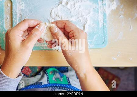 Weibliche Hände, die Teigbecher für Klößchen glätten. Stockfoto
