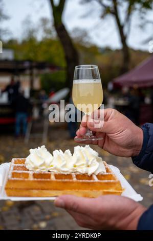Weinfest in Schengen, Luxemburg, französischen oder luxemburgischen Waffeln mit Schlagsahne und einem Glas Jungwein, der im Herbst im Freien gegessen wird Stockfoto