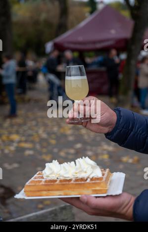 Weinfest in Schengen, Luxemburg, französischen oder luxemburgischen Waffeln mit Schlagsahne und einem Glas Jungwein, der im Herbst im Freien gegessen wird Stockfoto