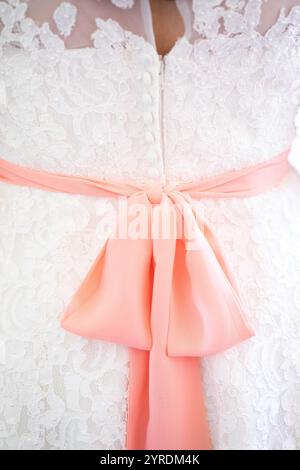 Elegantes Hochzeitskleid mit weißer Spitze und zartem rosa Schleifendetail Stockfoto