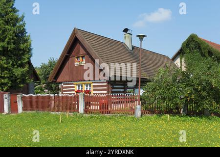 Kleines Holzhaus mit braunem Dach, umgeben von einem Gartenzaun und einem blühenden Garten, altes Holzhaus, Vesec u Sobotky, Dorfschutz A Stockfoto