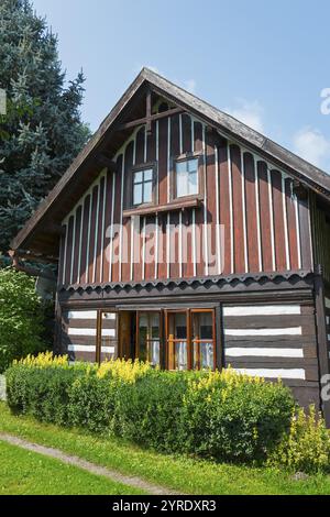 Stilvolles Holzhaus mit Holzbalken und grünen Büschen im Vordergrund, harmonisch in die Natur integriert, altes Holzhaus, Vesec u Sobotky, Teufel Stockfoto