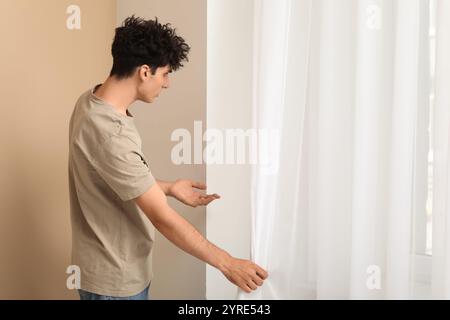 Junger Mann mit Schimmel an der Wand in der Nähe des Fensters zu Hause Stockfoto