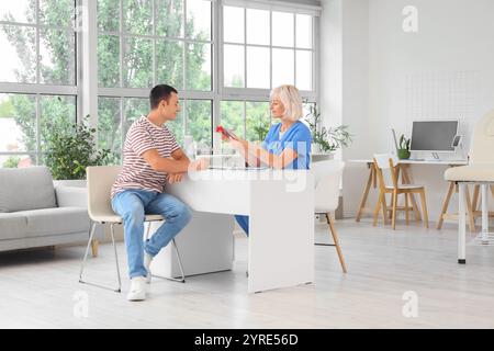Endokrinologin zeigt Schilddrüsenmodell beim Mann in der Klinik Stockfoto