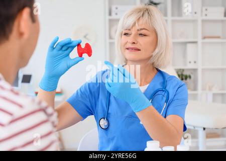 Endokrinologin zeigt Schilddrüsenmodell beim Mann in der Klinik Stockfoto