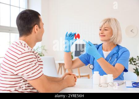 Endokrinologin zeigt Schilddrüsenmodell beim Mann in der Klinik Stockfoto