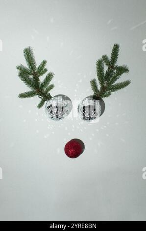 Weihnachtskugeln mit Rentiergeweih aus immergrünen Zweigen auf weißem Hintergrund. Minimales Silvester-Weihnachtskonzept. Flache Lagen. Stockfoto