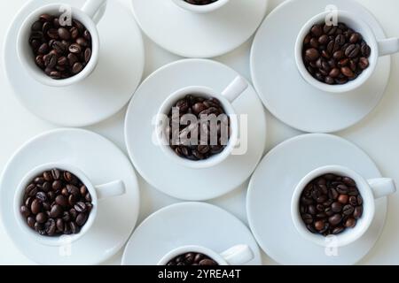 Weiße Kaffeetassen mit Kaffeebohnen auf einem weißen Tisch, Blick von oben Stockfoto