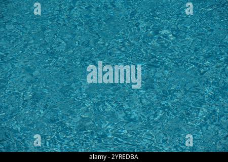 Wasserstruktur. Blick auf die Oberfläche des Swimmingpools. Blauer Wasserhintergrund. Blauer Hintergrund mit Wasserstruktur. Oberfläche des Beckenwassers. Stockfoto