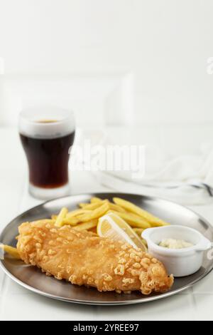 Fish and Chips ist ein heißes Gericht aus gebratenem Fisch in Mehl Batter, serviert mit Chips oder Pommes Frites und Cola. Auf Metallplatte Stockfoto