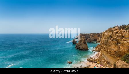 Viele Touristen genießen an einem sonnigen Sommertag das türkisfarbene Wasser und die goldenen Klippen am Strand praia dona ana in lagoa, algarve, portugal Stockfoto