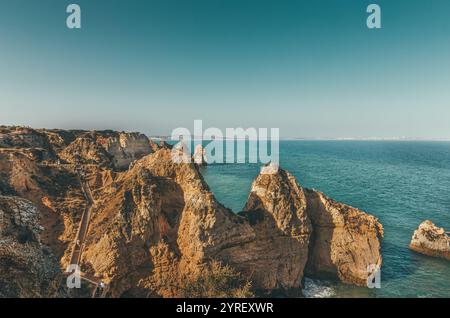 Touristen, die eine Holztreppe auf einer Klippe am malerischen Ort ponta da piedade in lagos, portugal, mit Felsformationen hinunterlaufen Stockfoto