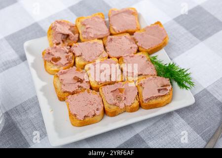 Knusprige Toasts mit glatter Fleischpastete auf weißem Teller Stockfoto