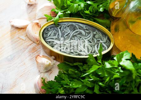 Eingelegte Aale in offener Dose mit Knoblauch am Tisch Stockfoto