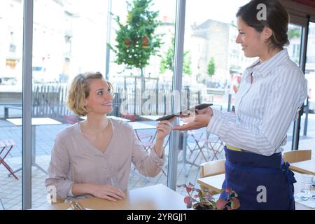 Eine junge Frau, die Essen bei einer Kellnerin bestellt Stockfoto