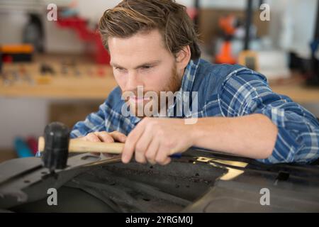 Mechaniker zur Festsetzung einer Autotür mit einem Hammer Stockfoto