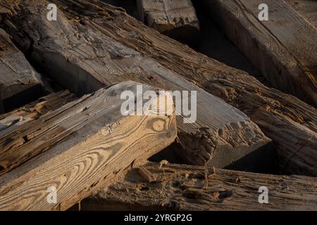 Detaillierte Ansicht der strukturierten Holzbalken, die Witterungseinflüsse und reiche Kornmuster unter warmer Beleuchtung zeigen. Stockfoto