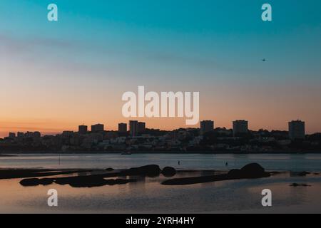 Farbenfroher Sonnenuntergang über dem Fluss douro mit der Skyline von Porto im Hintergrund und einem Flugzeug fliegen, Cabedelo, Vila Nova de Gaia, Portugal Stockfoto