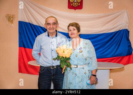 Ein russisches Paar feiert seinen goldenen Hochzeitstag im Standesamt. Das ältere Paar, beide über 70 Jahre alt, trägt stolz Medaillen, mit dem Stockfoto