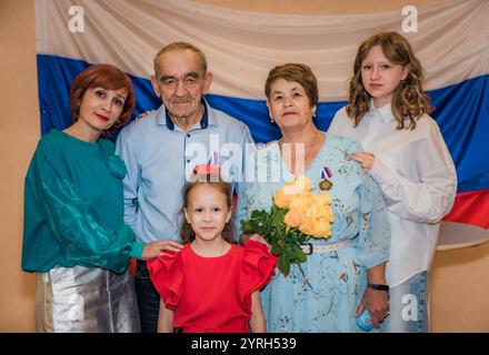 Eine russische Familie feiert ihren goldenen Hochzeitstag im Standesamt. Das ältere Ehepaar, über 70 Jahre alt, trägt stolz Medaillen, mit seiner dau Stockfoto