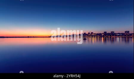 Stadtlichter reflektieren bei Sonnenuntergang auf dem Fluss douro mit orangefarbenen, rosa, lila und blauen Farbverläufen am Himmel in vila nova de gaia, portugal Stockfoto