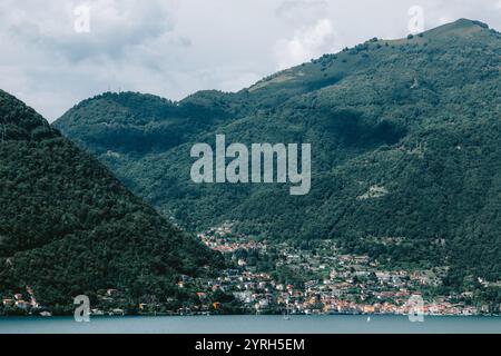 Der Comer See in den italienischen alpen bietet einen ruhigen Blick auf Dörfer an Berghängen, die sich in ruhigen Gewässern unter bewölktem Himmel spiegeln. Aus Nesso Stockfoto