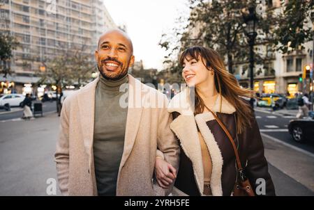 Ein fröhliches Paar schlendert Hand in Hand durch die Straßen der Stadt und genießt einen Tag voller Shopping. Stockfoto