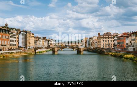 Ponte vecchio reflektiert auf dem Fluss arno unter einem bewölkten blauen Himmel mit historischen Gebäuden auf beiden Seiten des Flusses in florenz, italien Stockfoto