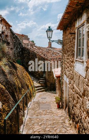 Steinhäuser und große Felsbrocken säumen eine enge Kopfsteinpflasterstraße in monsanto, portugal, einem historischen Dorf Stockfoto