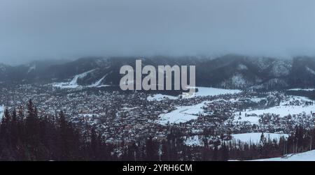 Panoramablick auf zakopane, polen, zeigt die Stadtlandschaft inmitten der verschneiten tatra an einem bewölkten Wintertag, was eine ruhige und friedliche Atmosphäre schafft Stockfoto