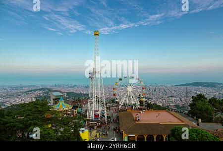 Beobachten Sie den Sonnenuntergang über barcelona, das Riesenrad und der Fallturm stehen hoch und schaffen Sie eine farbenfrohe Szene vom Berg tibidabo mit Blick auf das mittelmeer Stockfoto
