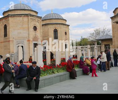 KONYA, TÜRKEI-23. APRIL 2017: Unbekannte Menschen sitzen und ruhen bei den osmanischen Grabsteinen und bunten Tulpen im Garten von Mevlana Museum Stockfoto