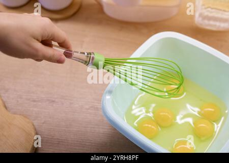 Ein Handrührer mit Eiern in einer Plastikschale mit hellgelbem Eigelb und geschäumtem weiß Stockfoto