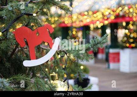 Neujahrsfeier, Weihnachtsbaumzweige mit Spielzeugpferd auf goldenem Lichterhintergrund Stockfoto