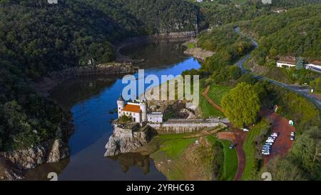 Atemberaubende Aussicht auf die Château de la Roche, eine malerische französische Burg, eingebettet am Fluss inmitten üppiger grüner Hügel. Perfekt für Reisen, Geschichte Stockfoto