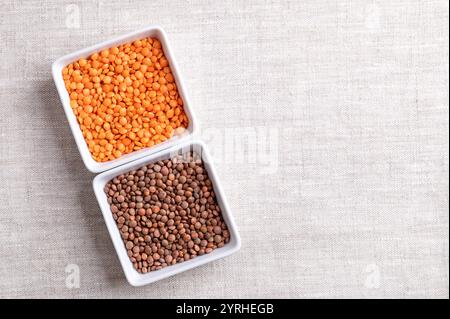 Getrocknete rote und braune Linsen in weißen Schüsseln auf Leinen. Geschälte und ungeschälte Berglinsen mit braunen Samenmänteln und orange-roten Linsenkernen. Stockfoto